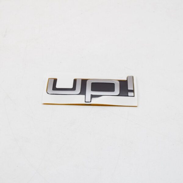 1S6853687FXC - Volkswagen UP Rear Emblem Badge 1S6853687FXC NEW GENUINE
