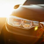 sunlit close up of a sleek modern car headlight with a lens flare effect at sunset. 19821955 scaled